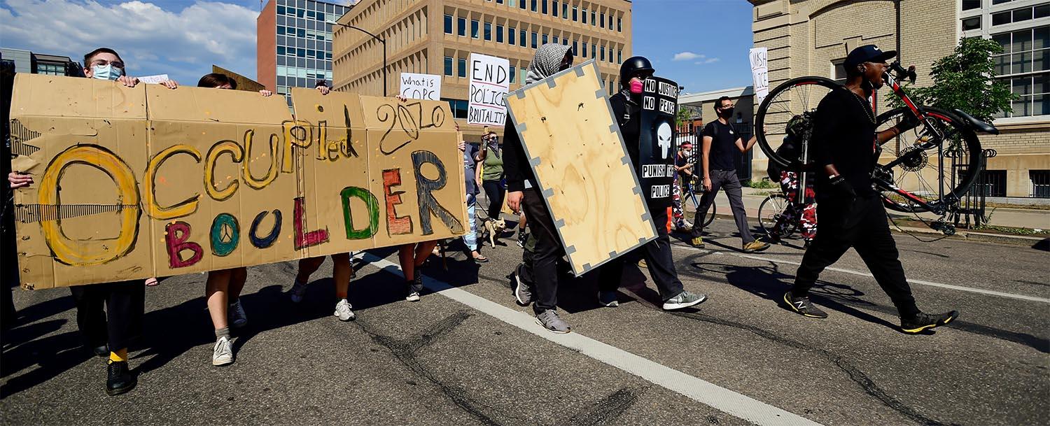 People marching with a banner that says "Occupied Boulder"